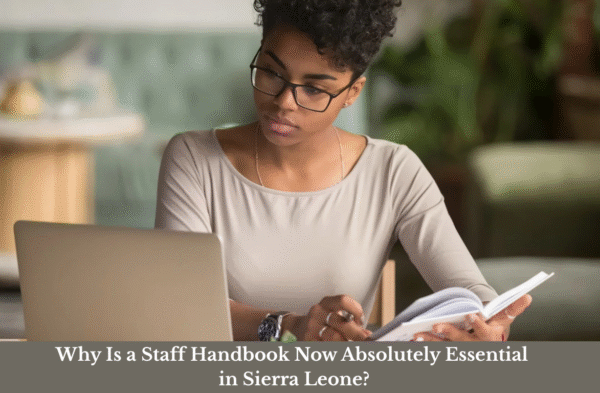Professional reading a staff handbook on the importance of workplace policies in Sierra Leone